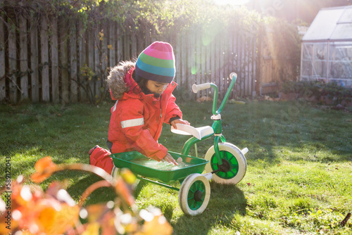 Girl (4-5) with tricycle in garden photo