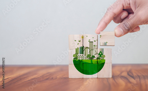 Eco friendly, green company culture concept. Carbon neutral and net zero target. Sustainable enviroment and business. Build green community. Hand holds wooden cubes with eco globe on grey background