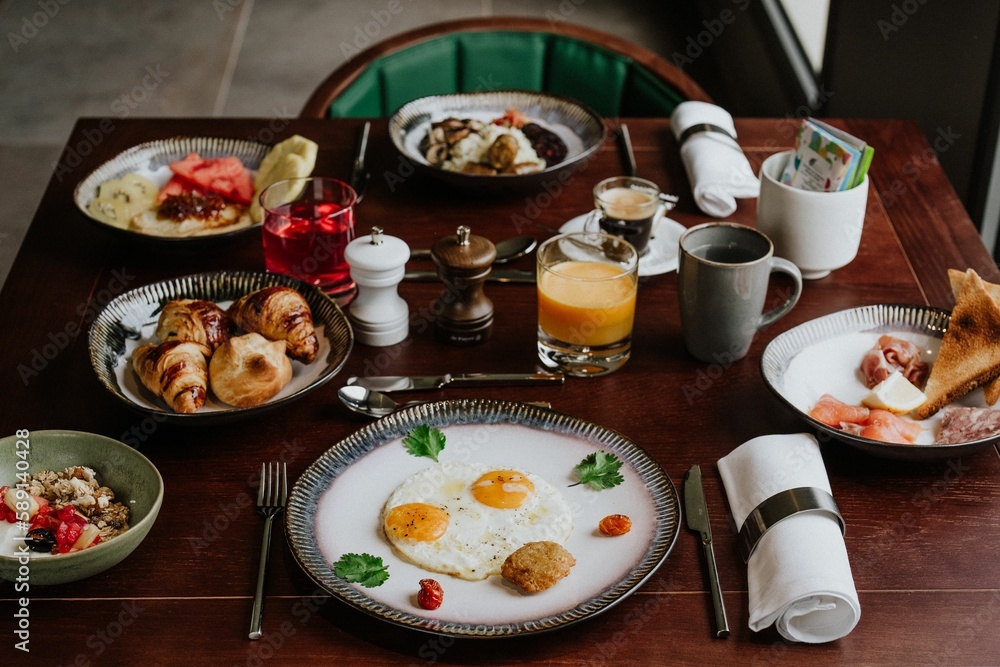 Delicious breakfast set on a wooden table with eggs, croissants, oatmeal and salad Delicious breakfast set on a wooden table with eggs, croissants, oatmeal and salad