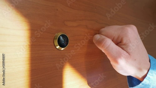 Person knocking on door. Male hand knocks at the door with a peephole. photo