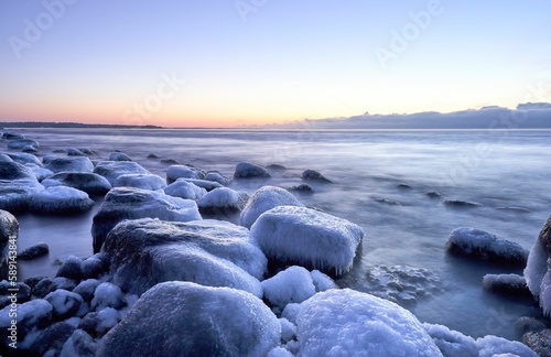 Closeup of rocks covered in the frost and ice in a frozen river under a cloudy sky
