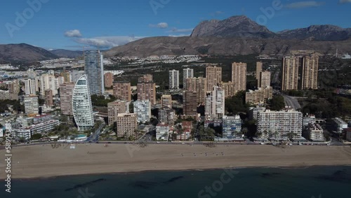 Sideways aerial reveal of the Poniente beach in Benidorm. Puigcampana and Aitana mountains in the background. photo