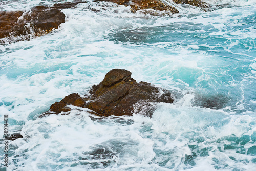 Pattern of sea surface and rocky shore. Coast island with blue turquoise water beats on rocky reef.