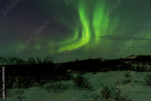 imagen de un paisaje nocturno nevado  con una aurora boreal en el cielo nocturno de Islandia 