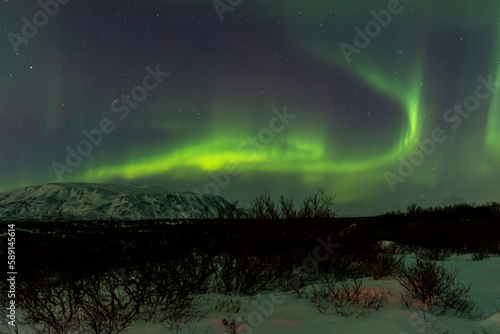 imagen nocturna de un paisaje nevado con una aurora boreal en el cielo nocturno de Islandia 