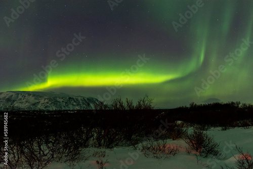 imagen paisaje nocturno con monta  as al fondo y una aurora boreal en el cielo estrellado de Islandia 