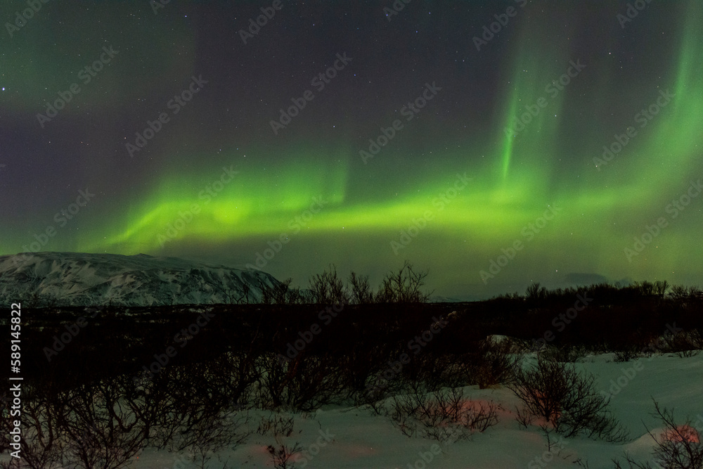 imagen nocturna de un paisaje nevado con una aurora boreal en el cielo nocturno de Islandia 