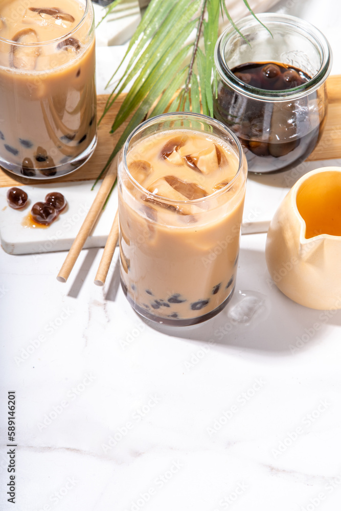 Iced tapioca coffee latte or boba pearl bubbles milk tea, asian trendy cold coffee drink with tapioca balls and crushed ice, on white marble background copy space Iced tapioca coffee latte or boba pearl bubbles milk tea, asian trendy cold coffee drink with tapioca balls and crushed ice, on white marble background copy space