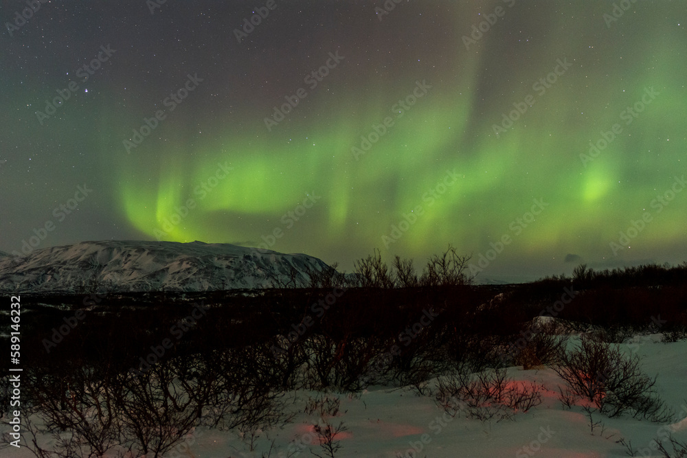 imagen nocturna de un paisaje nevado con una aurora boreal en el cielo nocturno de Islandia