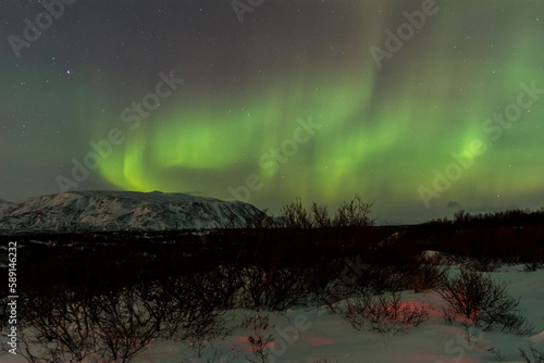 imagen nocturna de un paisaje nevado con una aurora boreal en el cielo nocturno de Islandia