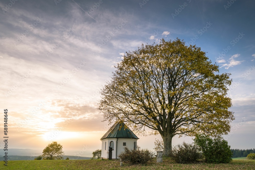Sunset landscape of a chapel under a huge autumn tree with a spectacular sky in the background Sunset landscape of a chapel under a huge autumn tree with a spectacular sky in the background