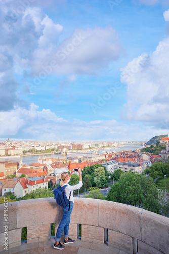 Enjoying vacation in Budapest. Young traveling woman taking photo of city view.