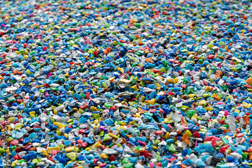Small pieces of crushed plastic. Crushed bottle caps for recycling. Plastic waste that will be mixed with plastic vergin. Concept reducing plastic.