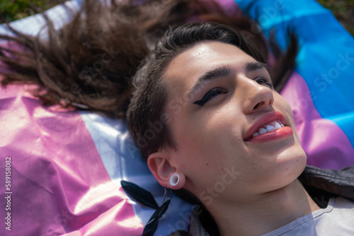 Fényképezés Overhead shot of a transsexual woman lying on the multicolored trans flag