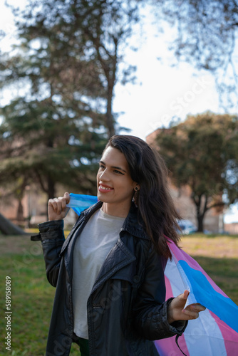 Overhead shot of a transsexual woman lying on the multicolored trans flag. We activate LGTBIQ+