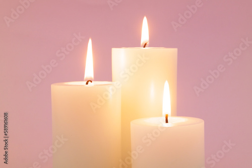 Close up of candles burning on pink background.