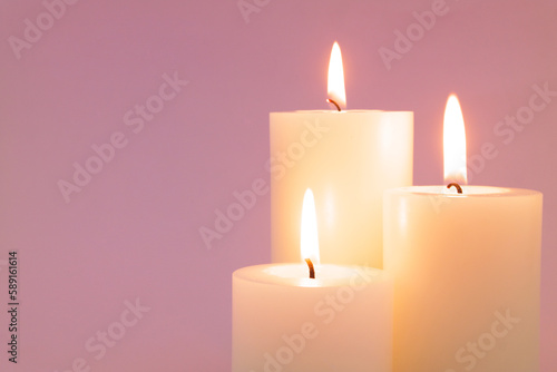 Burning candles on pink background close up. Copy space for text. 
