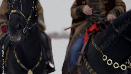 people on horseback, closeup view of black horse muzzle, historical reconstruction and fairytale photo