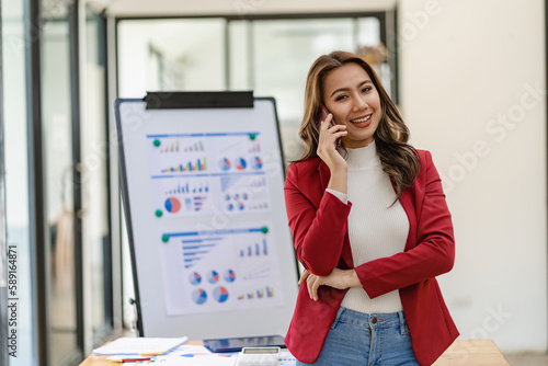 Serious asian businesswoman using customer service phone sitting at table, sales manager focused woman on mobile business phone discussing work with customer in office © ArLawKa