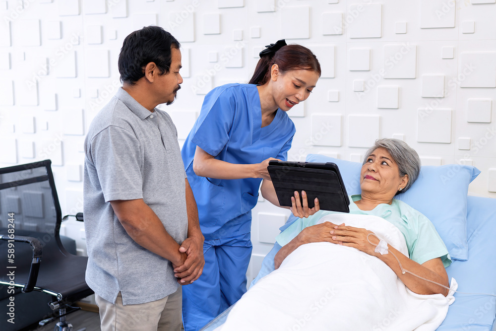 Nurse showing medical insurance data in digital tablet near bed of patient with relative stand by