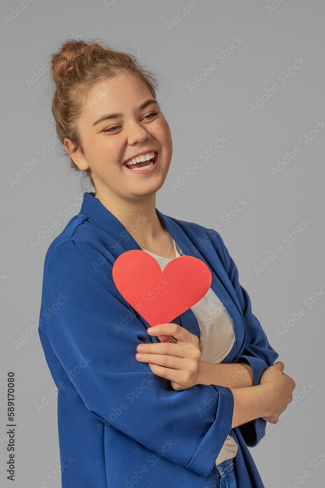 Vertical image of a girl with a huge smile with a paper heart for Valentine's Day Vertical image of a girl with a huge smile with a paper heart for Valentine's Day