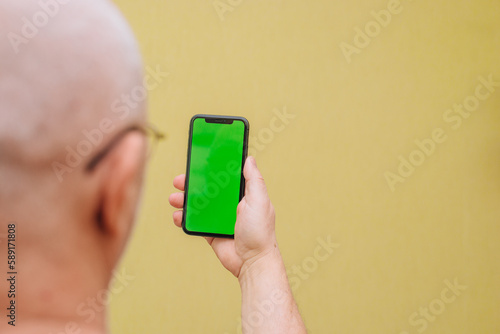Close-up of a man holding a new black smartphone with a blank screen. Mobile phone with green screen copy text
