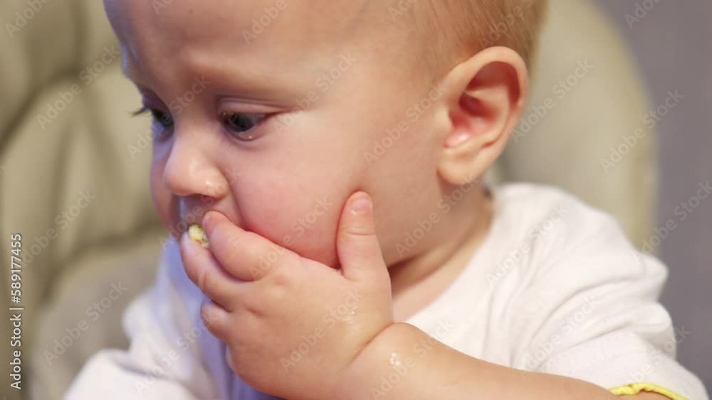 close-up child kid feeding high chair, toddler baby eating cracker cookies. first healthy diet. learning eat feed himself. mouth chewing crumbs helping hands hold, capricious crying baby hungry close-up child kid feeding high chair, toddler baby eating cracker cookies. first healthy diet. learning eat feed himself. mouth chewing crumbs helping hands hold, capricious crying baby hungry