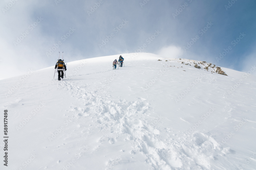 Mountaineers walking up along a snowy ridge with the skis in the backpack. Skier on the climbing track for freeride-descent. Backcountry skiers. ski free rider climbs the slope into deep snow powder