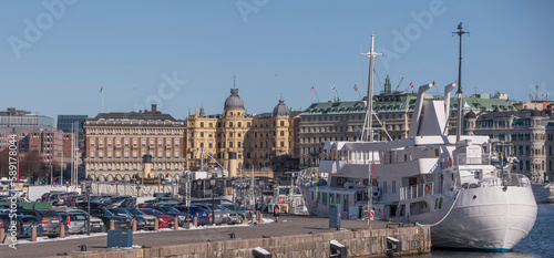 Pier crowded with parked cars, the ship Teaterbåten moored at the pier Skeppsbron, hotel and offices in the background, a sunny spring day in Stockholm