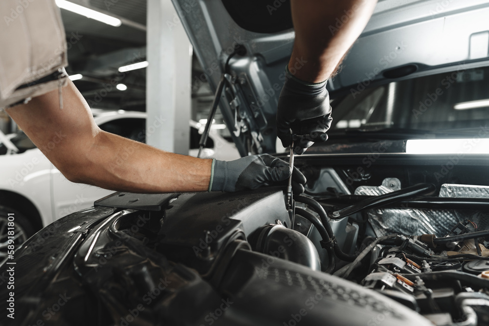 Close up of mechanic's hands repairing car engine in car service Close up of mechanic's hands repairing car engine in car service