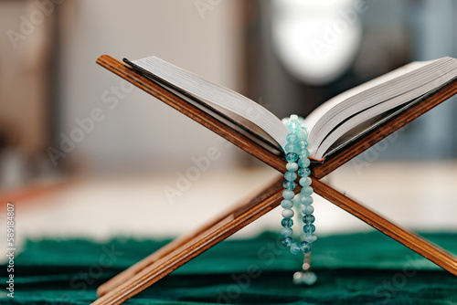 Holy Quran with prayer rosary beads on wooden stand photo