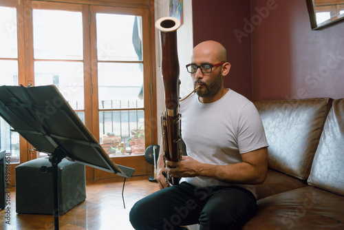 young latino man playing the bassoon at home photo