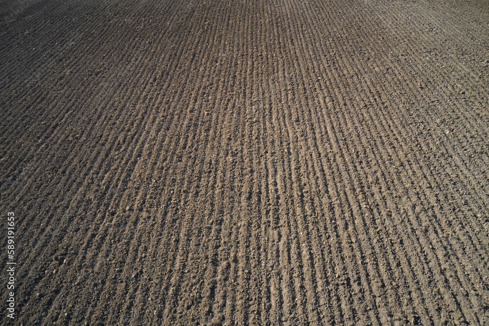Rows of soil before planting. Furrows row pattern in a plowed field prepared for planting crops in spring Rows of soil before planting. Furrows row pattern in a plowed field prepared for planting crops in spring