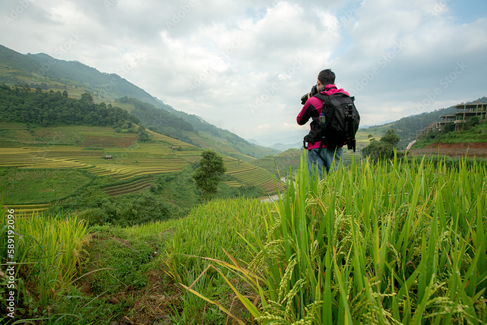 Tourist is standing on the viewpoint and take picture of rice terraces scenery at Mu Cang Chai in the north of Vietnam.