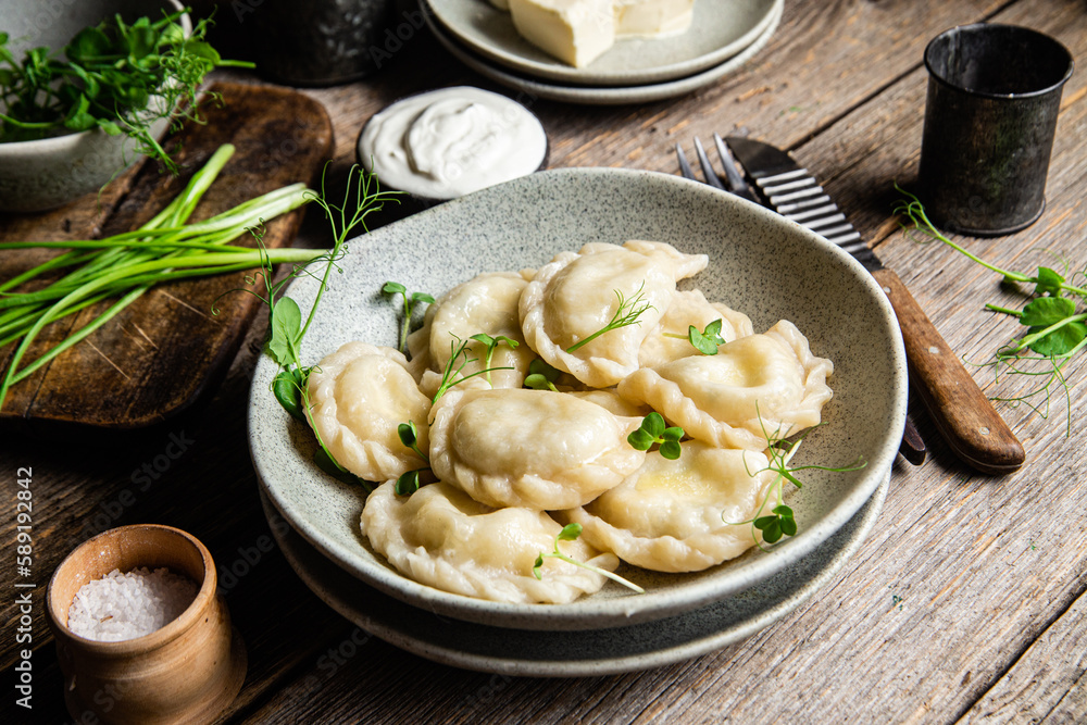 Vareniki with feta and herbs in a plate on a wooden table Vareniki with feta and herbs in a plate on a wooden table