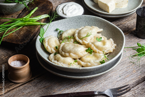 Vareniki with feta and herbs in a plate on a wooden table