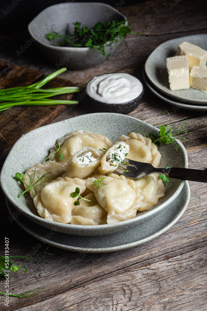 Vareniki with feta and herbs in a plate on a wooden table Vareniki with feta and herbs in a plate on a wooden table