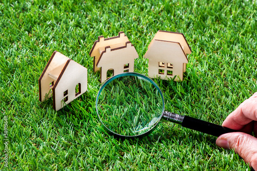芝生の上のミニチュアの家と虫眼鏡
