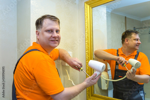 Man repairing electric hair dryer in bathroom at home.