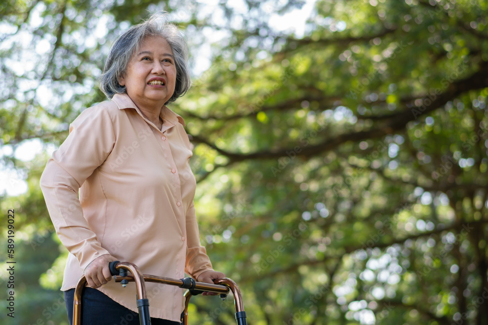 Happy old elderly Asian woman uses a walker for osteoarthritis