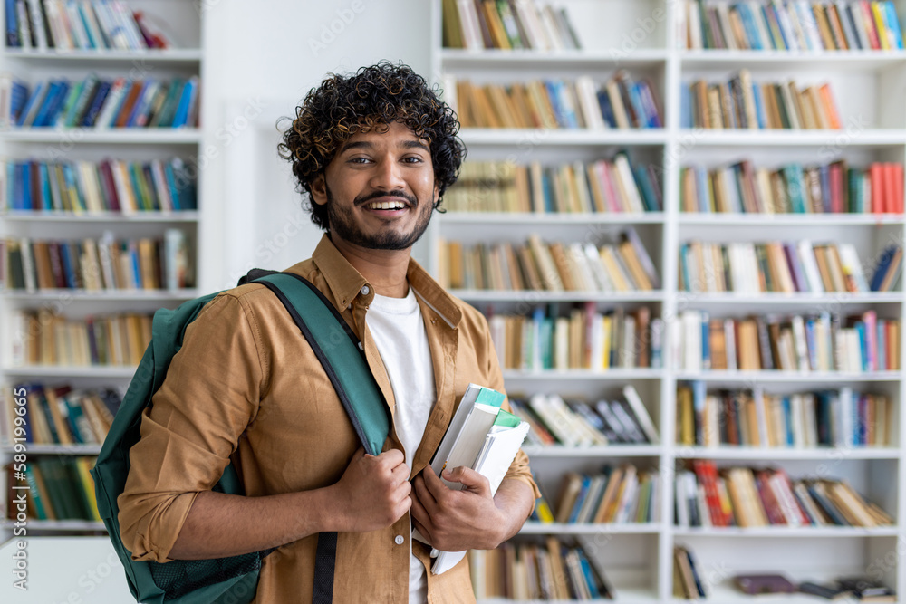 © Liubomir - Portrait of happy satisfied african american student with curly hair, guy with books and backpack standing in university academic library smiling and looking at camera. © Liubomir - Portrait of happy satisfied african american student with curly hair, guy with books and backpack standing in university academic library smiling and looking at camera.