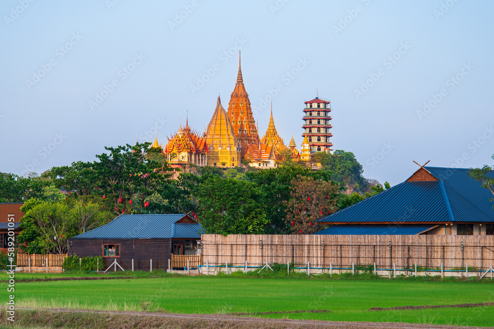 Fototapeta premium Wat Tham Seua temple with green rice filed in the sunset time at Kanchanaburi Thailand