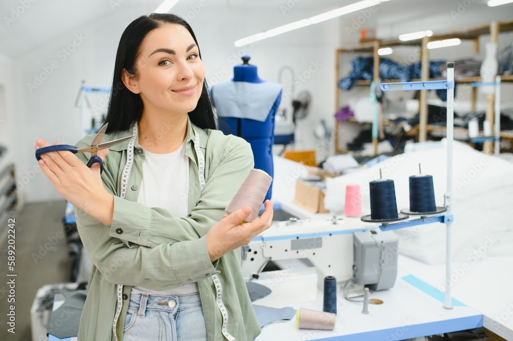 Obraz premium Beautiful young woman sewing clothes with sewing machine.