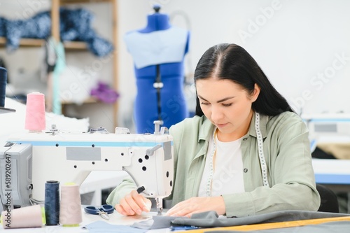 Young woman working as seamstress in clothing factory.