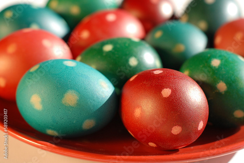 Multi colors polka-dotted Easter eggs on a red plate. on a red plate. Easter symbol. Close up Spring festive decoration.