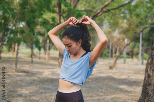 Young woman tied her hair before practicing exercise, doing stretching out before running or jogging. Concept of healthy life, relaxation ,recreation. City life style. Body movement. warm up