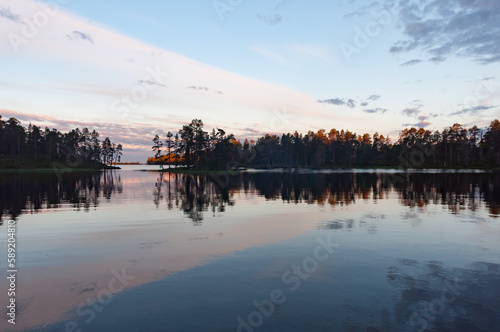Clouds reflected on the surface of a calm lake Inarijärvi in Lapland, Finland with forested islands © Jani Katajisto