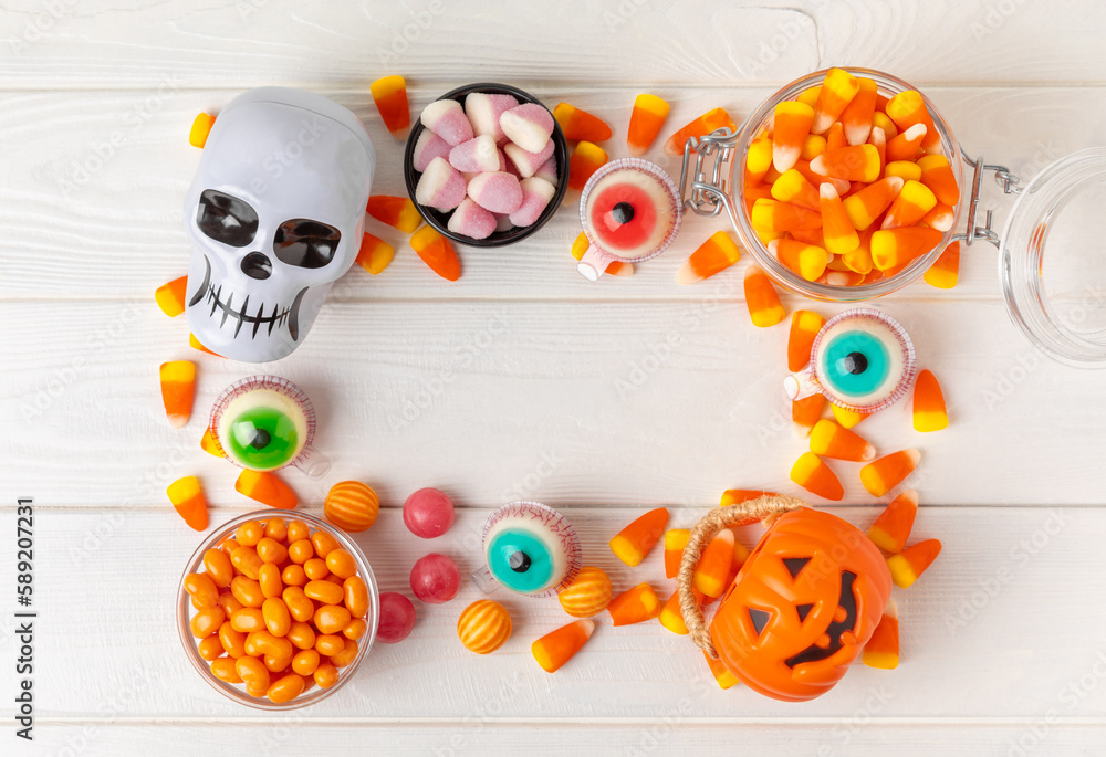 Fototapeta premium Halloween candy corn,jelly eye, pumpkin candy, sugar skull in different bowls on white background.Classic candy sweets for Halloween with.Halloween holiday concept with candy corn and jack o lantern.