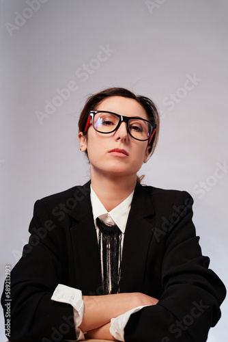 Happy cheerful manager woman in dark suit looking at camera. Serious lady in glasses and black jacket posing on isolated background. High quality vertical photo