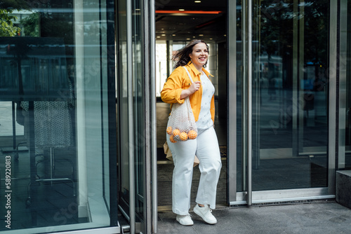 Size-inclusive body positivity advocates for acceptance and celebration of all body sizes and shapes, including plus-size or overweight. Happy curvy young woman in yellow cloth on city street